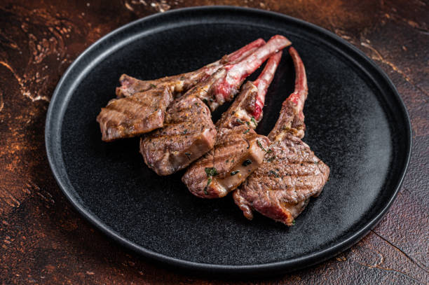 istock BBQ Grilled lamb chops steaks in a plate. Dark background. Top view 1351221498