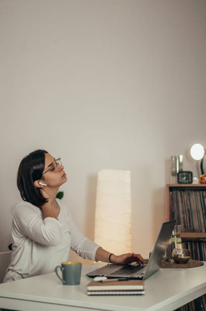 istock Beautiful woman having back and neck pain while using a laptop at home 1351222412