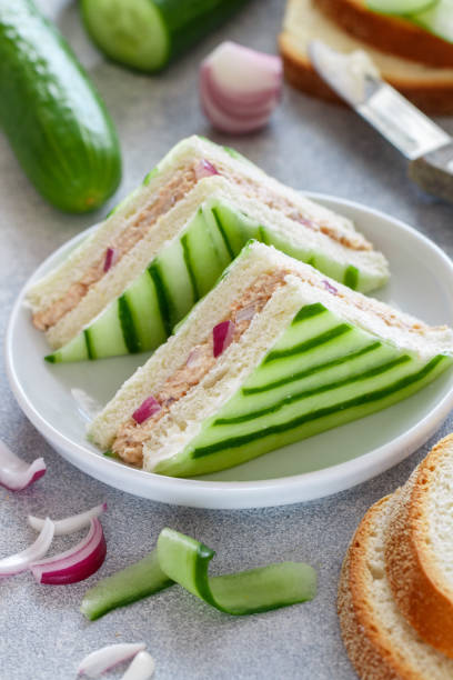 Traditional English tea sandwiches with salmon, red onion, cottage cheese (cream cheese, ricotta) and fresh cucumber. A light appetiser for gourmets. Selective focus Traditional English tea sandwiches with salmon, red onion, cottage cheese (cream cheese, ricotta) and fresh cucumber. A light appetiser for gourmets. Selective focus appetiser stock pictures, royalty-free photos & images