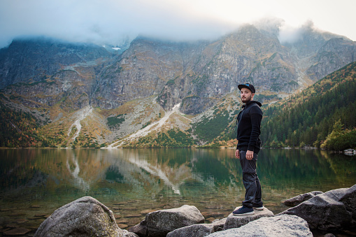 Tourist  near the mountain lake Morskie Oko in Tatra National Park, Poland. Happy hiker man  on the picturesque lake in the mountains in autumn.