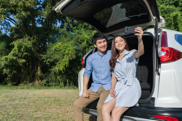 istock couple in love sitting and using smartphone taking a selfie in open car back 1351233148