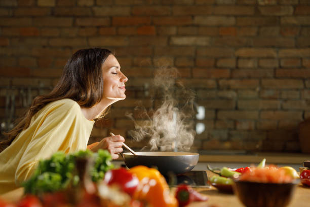 istock Young woman enjoying while cooking meal in the kitchen. 1351234533