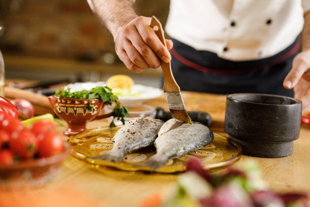 istock Unrecognizable chef brushing sea bream before making lunch in the kitchen. 1351234905