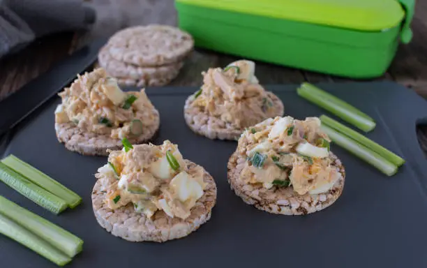 High protein meal for bodybuilding with a  egg  tuna salad served with brown rice cracker and celery sticks on a cutting board