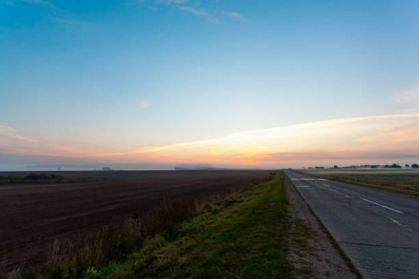 istock An empty asphalt road through the fields and forest in a thick fog at sunrise 1351237264