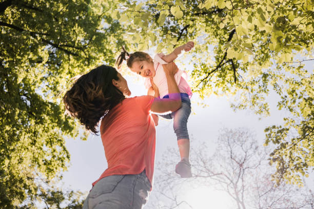 istock Below view of single mother throwing her daughter in nature. 1351237393
