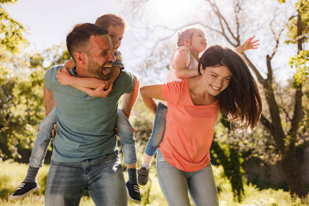 istock Playful family having fun while piggybacking in springtime. 1351237423