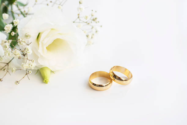 istock White flowers and two golden wedding rings on white background. 1351238201