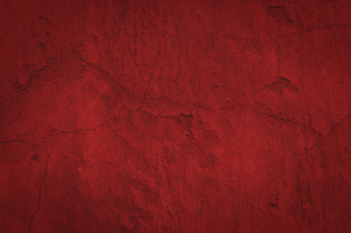 Red gloomy background with dark vignette and cracks on a rough surface. Classic backdrop for design