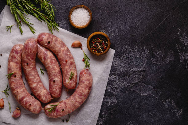 istock Raw sausages and ingredients for cooking on a black stone table 1351243026