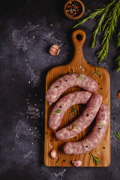 istock Raw sausages and ingredients for cooking on a black stone table 1351243123
