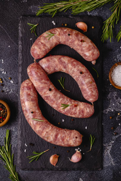 istock Raw sausages and ingredients for cooking on a black stone table 1351243126