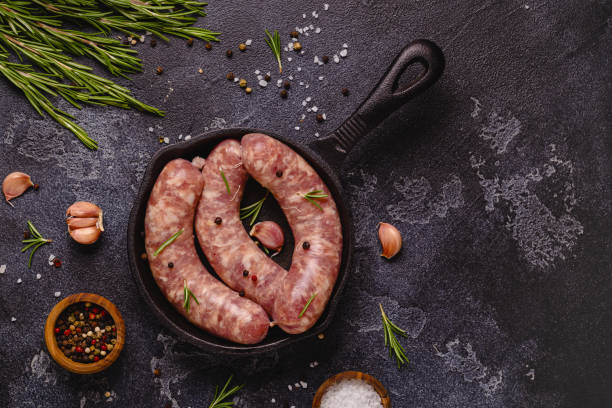 istock Raw sausages and ingredients for cooking on a black stone table 1351243217