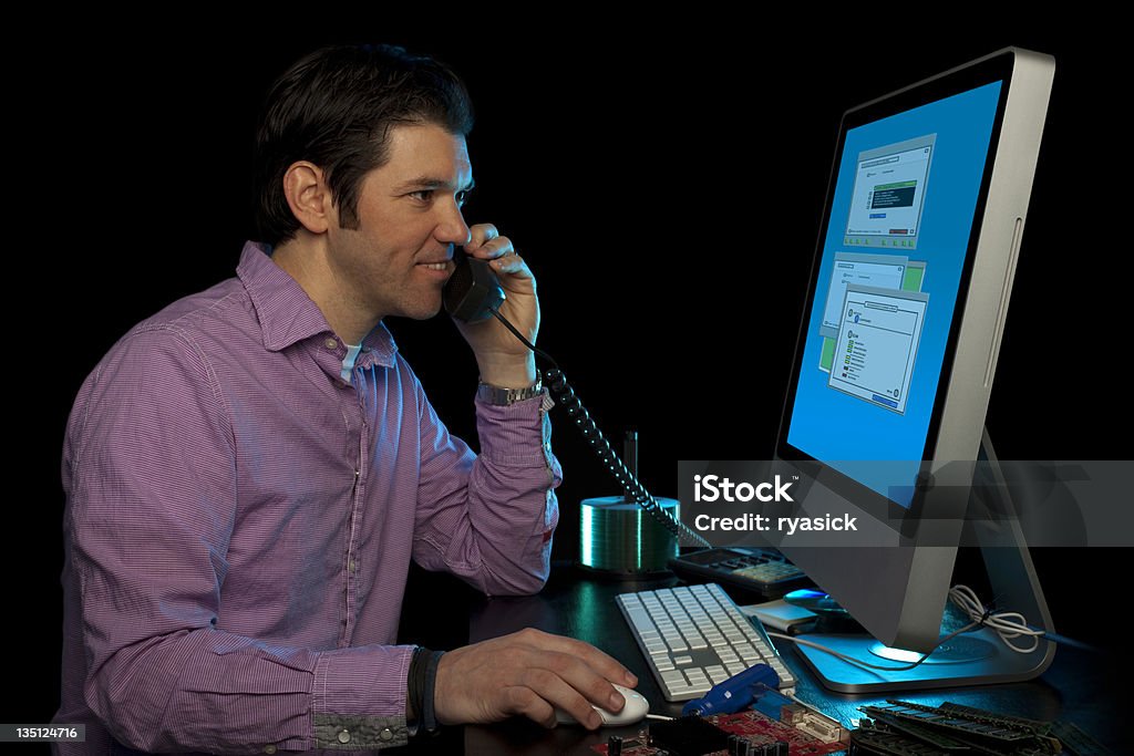 IT Service Technician Helping Customers Over The Phone An IT technician services diagnostic problems via his networked computer.Note: screen graphics self-created. Adult Stock Photo