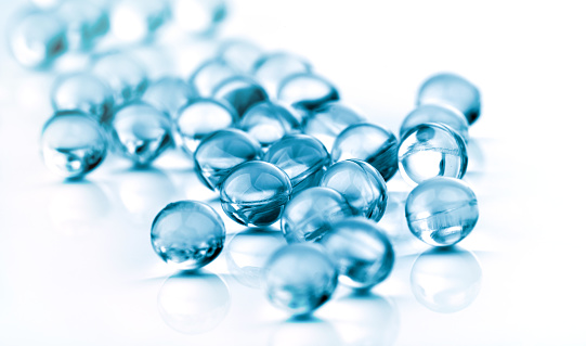 Abstract clear blue colored pills against white. background