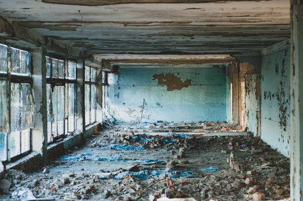 istock Abandoned building with dirty broken glass, close-up view inside, peeling paint and plaster, construction debris on floor 1351248002