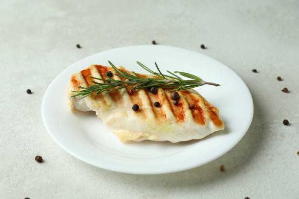 istock Plate with grilled chicken breast on white textured table 1351250330