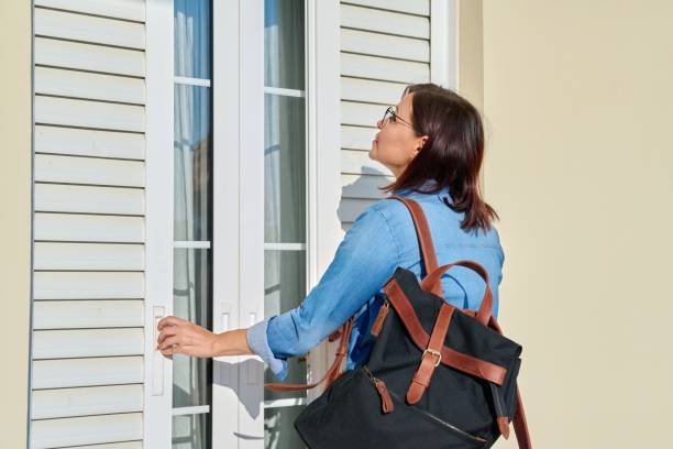 istock Woman with backpack opening shutters outside doors on window 1351255869