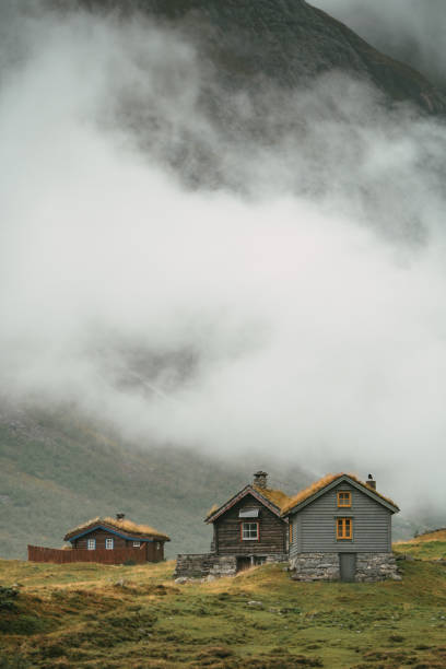 Majestic mountain range covered with fog and huts in the valley
