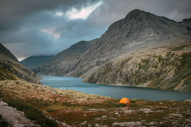 istock Exploring wilderness. Mysterious mountain landscape with lake. Camp with tent 1351256457