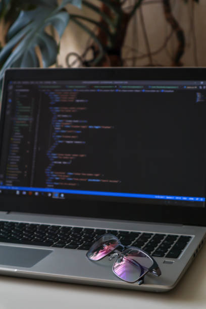 istock Man's glasses are lying on a laptop with code at home. Home office with plants 1351256868