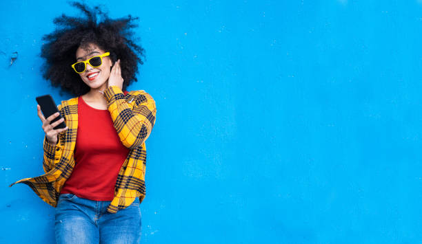 istock Smiling american-african woman using smart phone on a blue background 1351257396