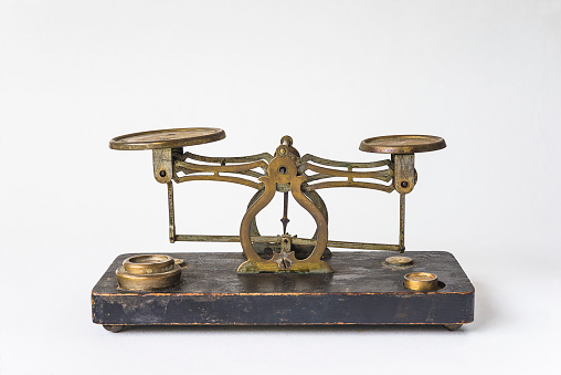 Antique two pan tray balance weight scales on vintage wooden table and white background.