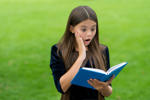 istock Surprise helps to study new things. Surprised child read study book outdoors. Knowledge and information. School library. Reading education. Motivation and interest. Attracting learners attention 1351259188