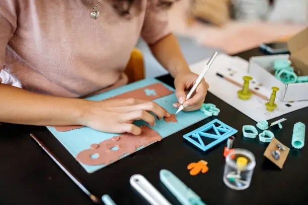 Young unrecognisable woman designing clay earrings