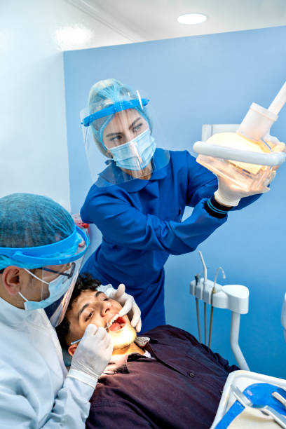istock Dentist with female assistant treating patient 1351262435