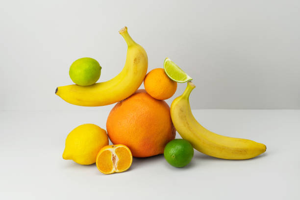 istock Fresh banana, grapefruit, lemon, lime slice, tangerine half balanced on grey background. Bright yellow, green and orange fruits with vitamins for salad. Healthy diet composition. Still life 1351266919