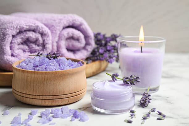 Cosmetic products and lavender flowers on white marble table