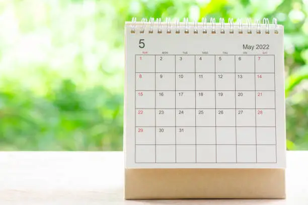 Photo of May month, Calendar desk 2022 for organizer to planning and reminder on wooden table with green nature background.