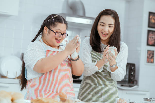 Down syndrome girl makes fruit smoothies in the kitchen at home with mom Down syndrome girl makes fruit smoothies in the kitchen at home with mom developmental disability stock pictures, royalty-free photos & images