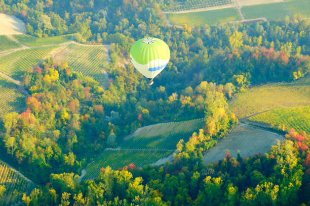 Aerostatic balloons are flying over the hills of Langhe (Piedmont, Northern Italy), covered by vineyards during fall season; UNESCO Site since 2014.