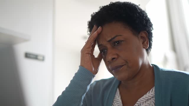 Worried mature woman with headache working at home