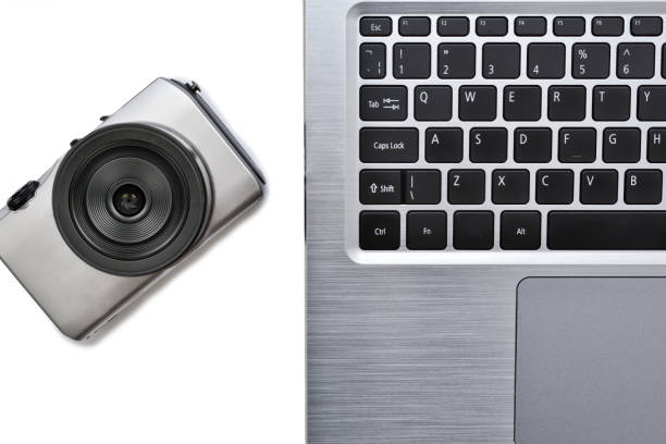 istock Laptop computer keyboard and photo camera on the desk. Digital devices and tools for shoot photos and work with images, write and prepares news and articles. Correspondent work and journalism concept. 1351280913