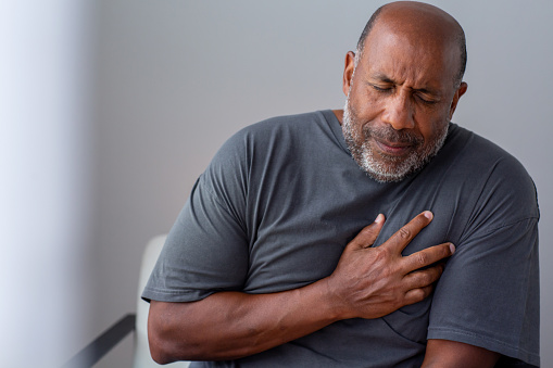 Mature man in pain holding his chest.