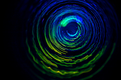 Abstract spinning glowing lines with blurred motion effect on a black background. Can be used as some technology, science background.