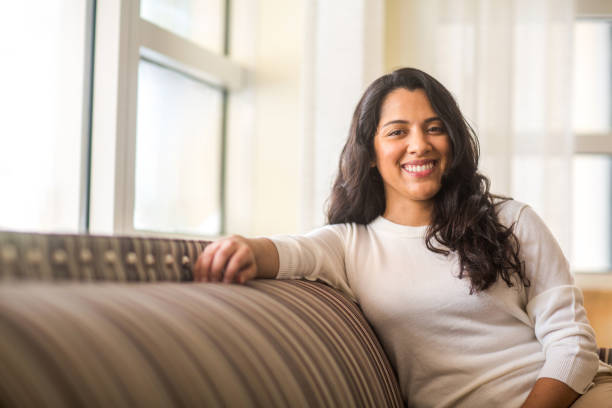 Hispanic woman sitting on the sofa smiling. stock photo