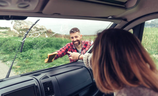 istock Man cleaning van windshield while woman pointing stain 1351284153