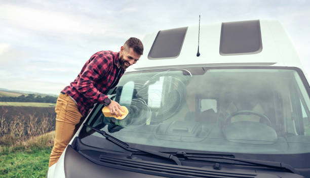 Man cleaning camper van glass outdoor stock photo