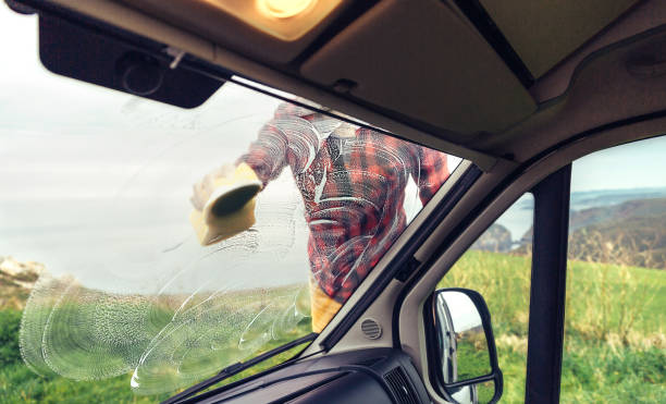 istock Man cleaning camper van windshield outdoor 1351284164