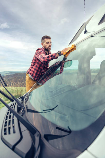 istock Man cleaning camper van windshield outdoor 1351284174