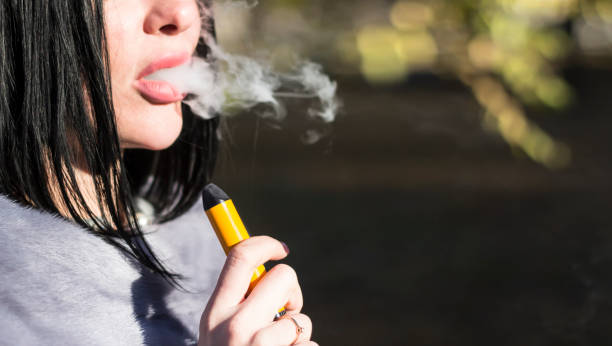 The girl smokes an electronic cigarette in the fresh air. The girl smokes an electronic cigarette in the fresh air. mink fur stock pictures, royalty-free photos & images