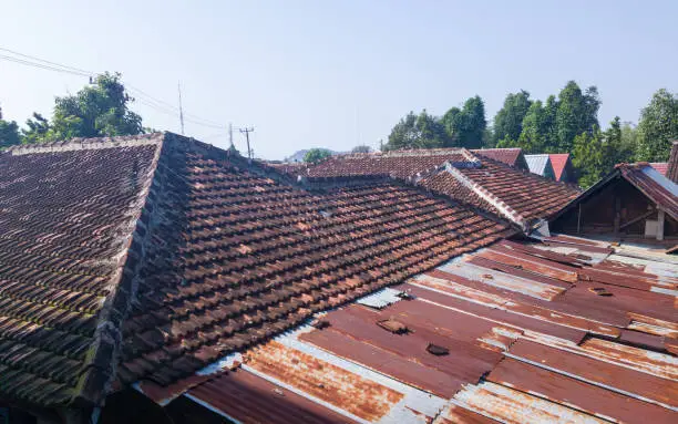 house roof made from brown clay rooftile and rusty iron sheet in the morning