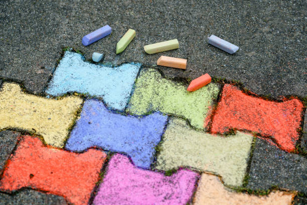 istock Figures painting with colorful chalks on ground on backyard. Children activity, drawing and creating pictures. Creative outdoors activity in summer. 1351290135