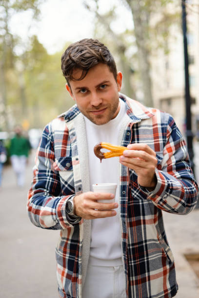 istock Man with churros with chocolate in street 1351292322