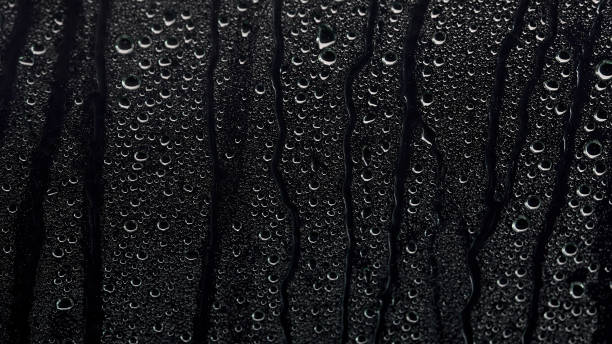 la pluie tombe sur un fond noir. l’arrière-plan peut être supprimé à l’aide d’un mode de fusion comme écran. - condensation photos et images de collection