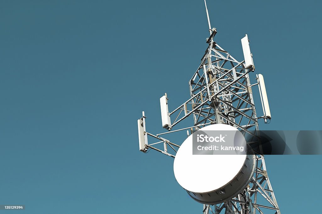 Telecommunications tower against a cloudy sky Mobile phone base station. Vivid sky color. Antenna - Aerial Stock Photo